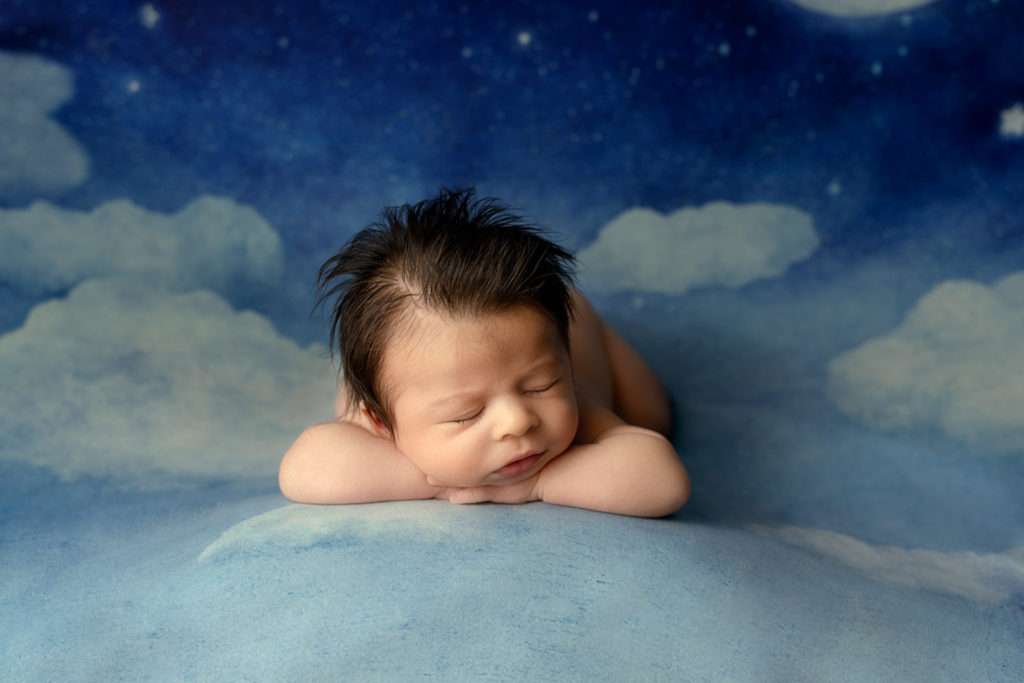 newborn baby boy with lot of hair sleeping on the blanket with clouds