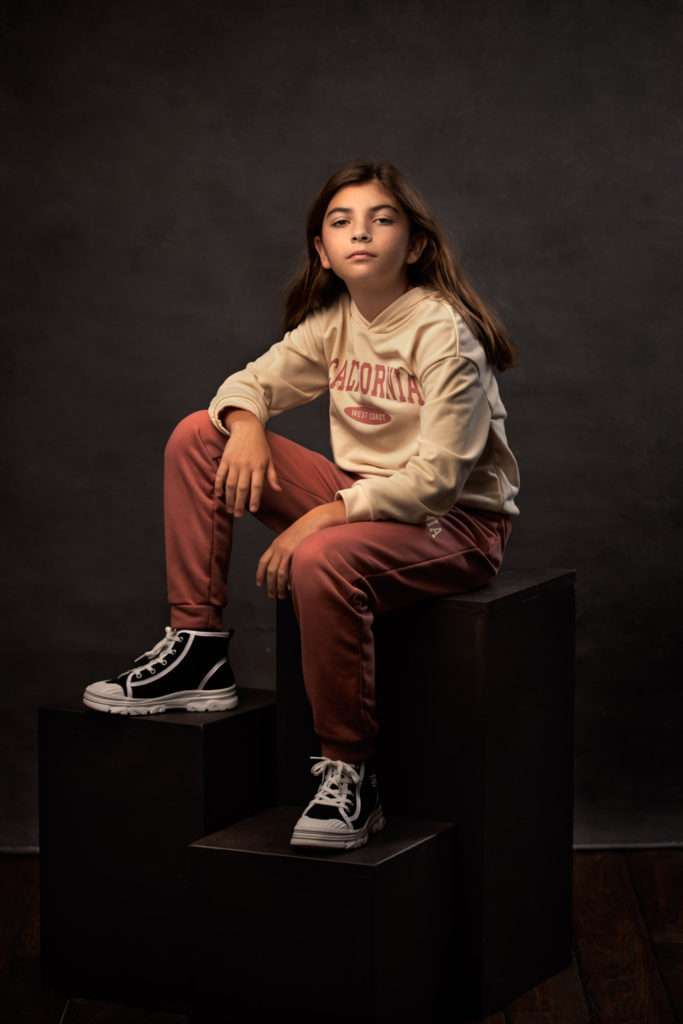 fine art studio portrait of a girl sitting on black boxes
