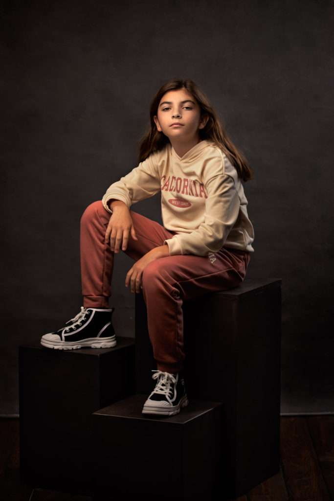 studio portrait of a girl sitting on the black posing blocks in the san diego photo studio