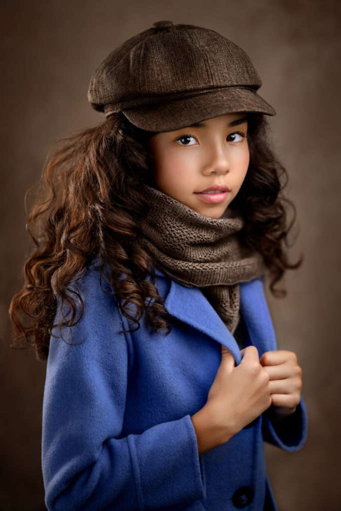 fine art portrait of a girl with dark curly hair and blue coat photographed in san diego photo studio by san dieog family photographer