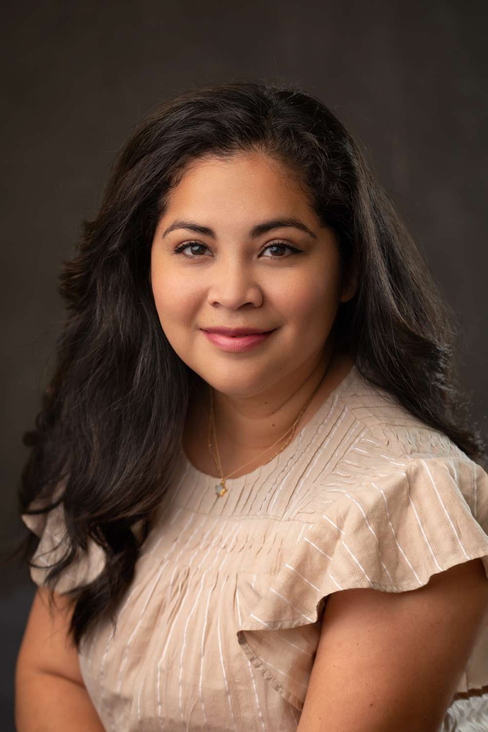 headshot of a woman with dark heir and in cream top