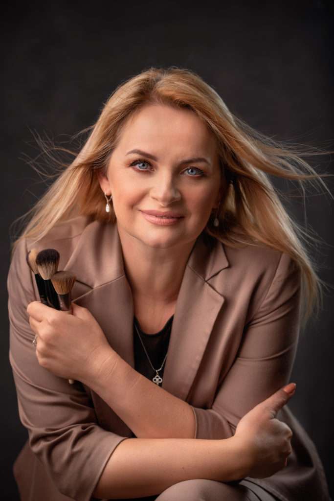 professional headshot of a make up artist holding make up brushes in taupe jacket by san diego professional headshot photographer