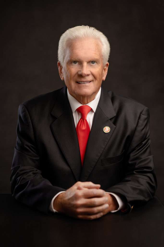 professionall headshot of a older men wearing black suit and red tie by san diego headshot photographer