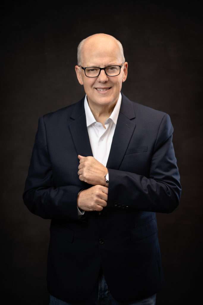 studio headshot of an older men with black suit and glasses by san diego headshot photographer