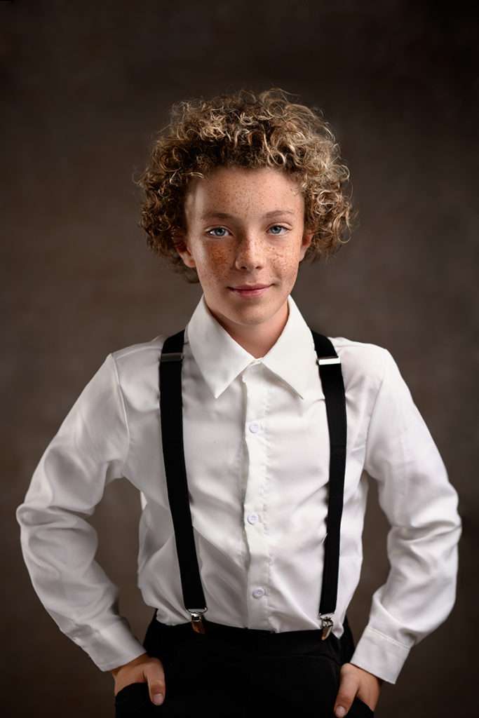 fine art portrait of a curly boy with freckles wearing white short and suspenders by san diego photographer